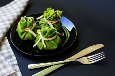 Siyah tabakta içi et dolu ıspanaklı krep, koyu sırt.