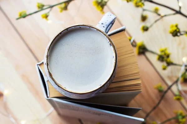 Cup of coffee and a book on a wooden background with yellow flowers. Workplace. Cozy breakfast. Spring concept