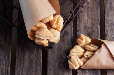 Süzme peynir ve şekerli kurabiyeler tahta arka planda kağıt bir zarfın içinde ayakları tırmalıyor.