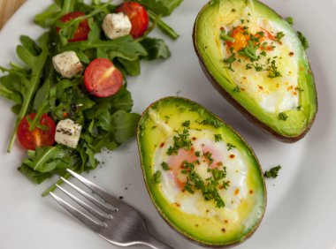 Maydanoz ve roket salata, domates ve peynir salatası ile serpilir yumurtalı kızarmış avokado