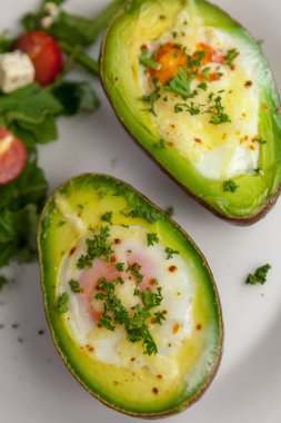 Maydanoz ve roket salata, domates ve peynir salatası ile serpilir yumurtalı kızarmış avokado