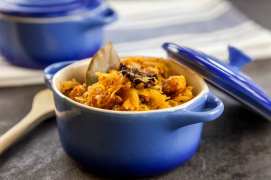 Bigos - lahana turşusu ile geleneksel Polonya yemeği ve et, pastırma ve mantarlı mavi seramik tencerede taze lahana