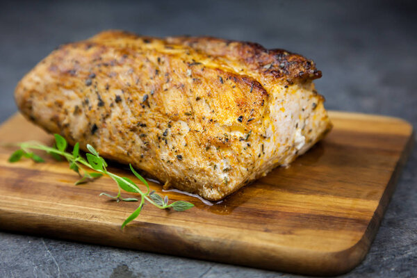 Roasted pork tenderloin with thyme on the wooden cutting board