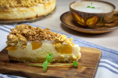 Cheesecake şeftali ahşap kesme tahtası üzerinde ile dilim. Kek ve kahve arka planda