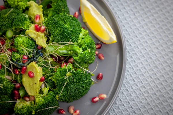 Healthy vegan food - broccoli salad with pomegranate and guacamole