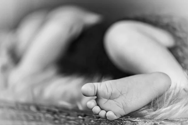 New born baby\'s foot, sleeping baby in the background - black and white