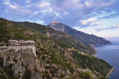 Vista ile ön plan ve dramatik bulutlar altında denize inen yamaçlar Simonos Petra manastırda Mt. Athos yarımadasında süpürme bir altın saat.