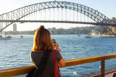 Yaz tatil gezisi sırasında Sydney Harbour Bridge fotoğrafını çekmek sırt çantası ile kadın turist.