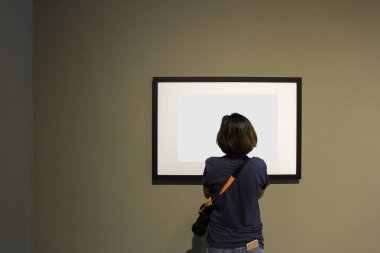 Kadın boş fotoğraf çerçevesi duvar Sanat Galerisi'nde arıyor.