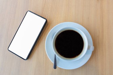 sahte şablon arka plan ve ahşap masa kahve Kupası fincan için boş beyaz ekran ile Smartphone
