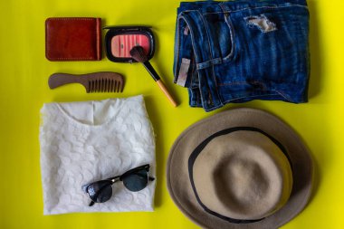 üstten görünüm seyahat hayat stlye güzelliği ile yırtık kot pantolon, güneş gözlüğü ve şapka sarı zemin üzerine makyaj