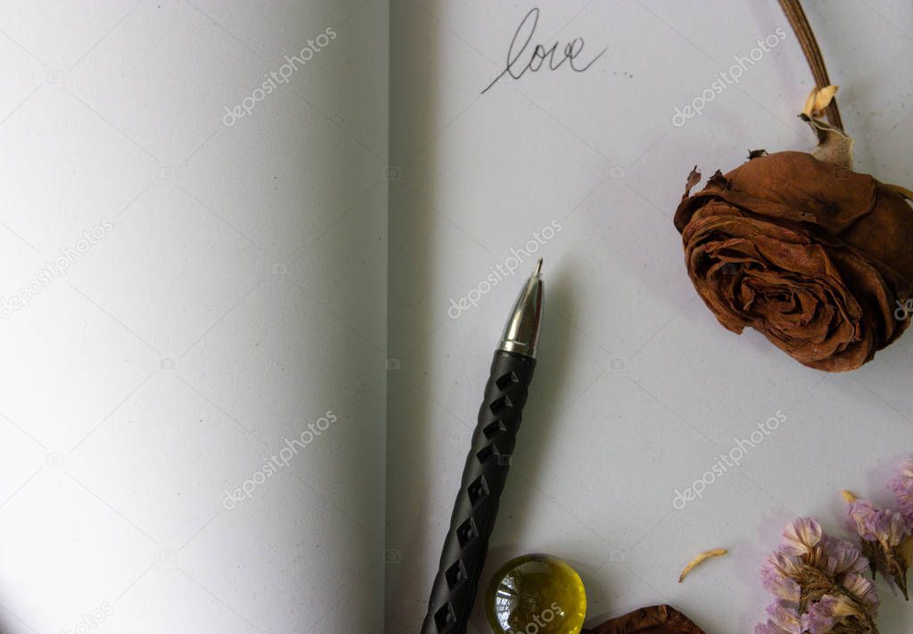 old  brown roses, dried lavender flowers, pen and love word on blank white book , love word,