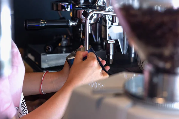 Asyalı kadın Barista holding sürahi ve süt hazırlanması için denetimleri sıcaklık cappuccino veya sütlü kahve için köpük