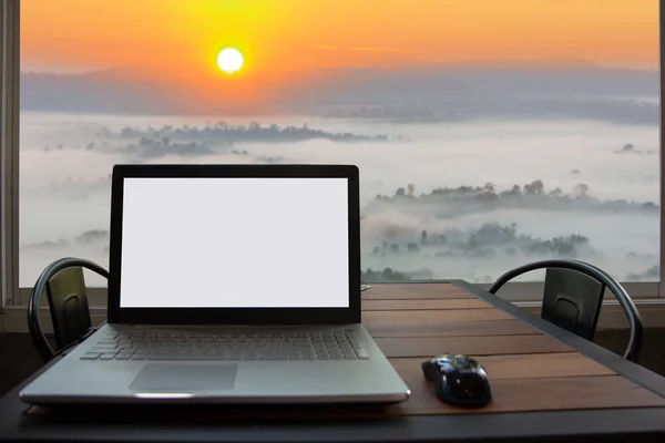 laptop için sahte şablon arka plan gündoğumu üzerinde dağ manzaralı masada kadar boş beyaz ekran ile.