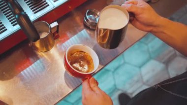 Kahveye süt koyan kahve sanatçısı. Kafede latte sanatı yapıyor.
