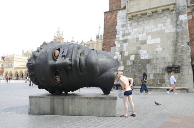 Kracow, Polonya - 25 Temmuz 2018: Çocuklar büyük içi boş bronz başından Main Market Square eski kasaba Krakow, Polonya'nın gözünde.