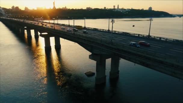 ドローン夕日キエフのドニエプル川を渡ってペイトンズ橋と平行します カメラの視野の太陽 空中映像 — ストック動画