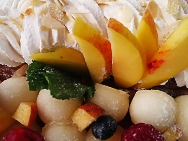 kavun topları, şeftali dilimleri, ahududu ve yaban mersini yanı sıra nane ve krem tatlı arka plan