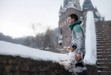 Genç bir adam ve bir köpek kalede. Senin evde beslenen hayvan ile yürümek. Köpek kış niteliğine