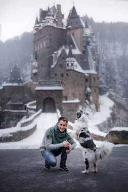 Genç bir adam ve bir köpek kalede. Senin evde beslenen hayvan ile yürümek. Köpek kış niteliğine