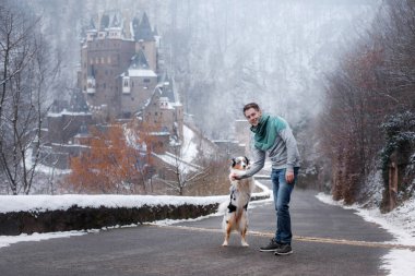 Genç adam ve bir köpek kalede. Senin evde beslenen hayvan ile yürümek. Kışın niteliğine Avustralyalı çoban