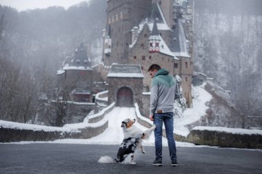 Genç adam ve bir köpek kalede. Senin evde beslenen hayvan ile yürümek. Kışın niteliğine Avustralyalı çoban
