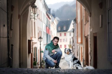 Şehirde bir köpek ile genç bir adam. bir evcil hayvan ile yürümek. Büyüleyici adam ve Avustralya Çoban