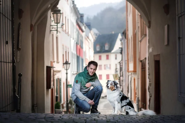 şehirde köpek ile genç adam. evcil hayvan ile yürümek. Büyüleyici adam ve Avustralya Çoban