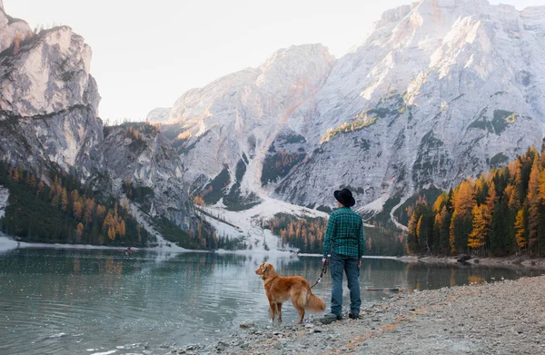 man with a dog at the famous mountain lake Braies in Italy. Traveling with a pet. High quality photo