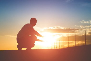 Güneş batımında tutan bir adam silüeti