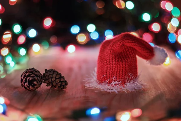 Rote Weihnachtsmütze Und Tannenzapfen Auf Dem Tisch Vor Einem Hintergrund — Stockfoto