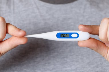 Bir adam bir elektronik termometre sıcaklığı 36,6 ile tutar