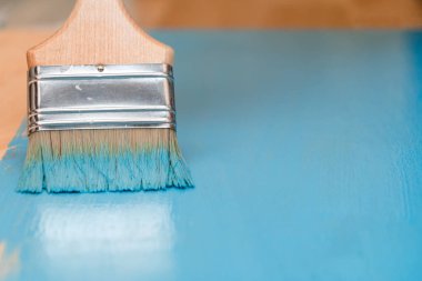 Bir boya fırçası kullanarak mavi boya ile ahşap yüzey boyama