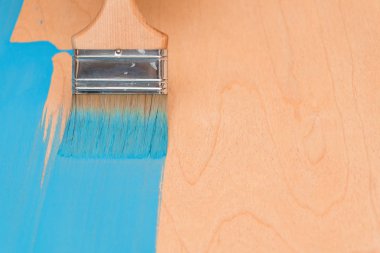 Bir boya fırçası kullanarak mavi boya ile ahşap yüzey boyama