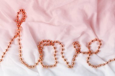 Beyaz kumaş arka plan üzerinde bir kelime aşk şeklinde boncuklar