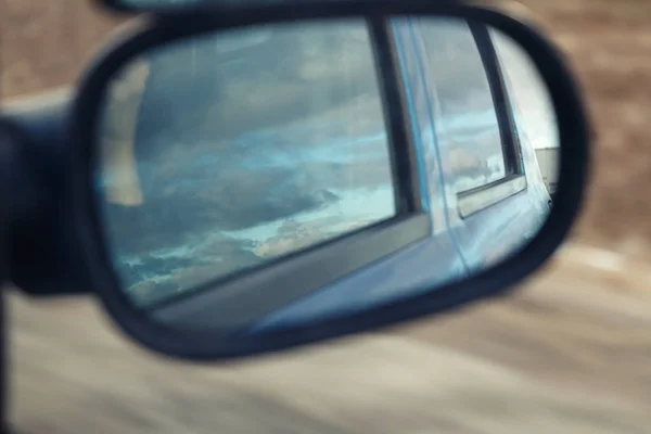 The reflection of the sky in the side mirror of the car