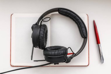 Açık boş defter ve kalem ve kulaklık beyaz bir tablo