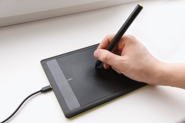Erkekler el bir kalemi kullanarak bir grafik tablet üzerinde çizer