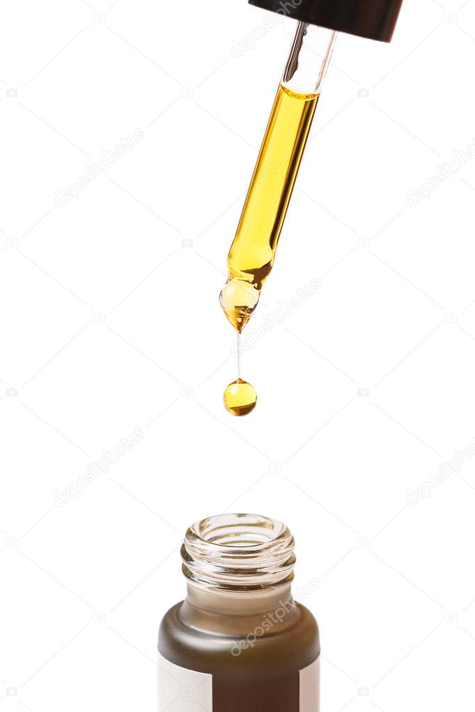A drop of cosmetic oil drips from the pipette into the bottle