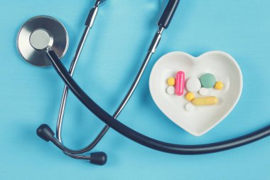 Steteskop ve çeşitli hap bir daire üzerinde kalp şeklinde bir