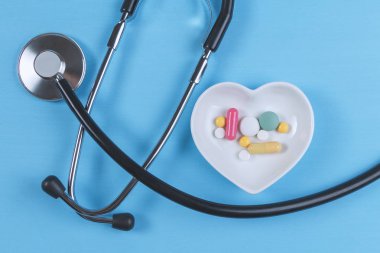 Steteskop ve çeşitli hap bir daire üzerinde kalp şeklinde bir