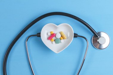 Steteskop ve çeşitli hap bir daire üzerinde kalp şeklinde bir