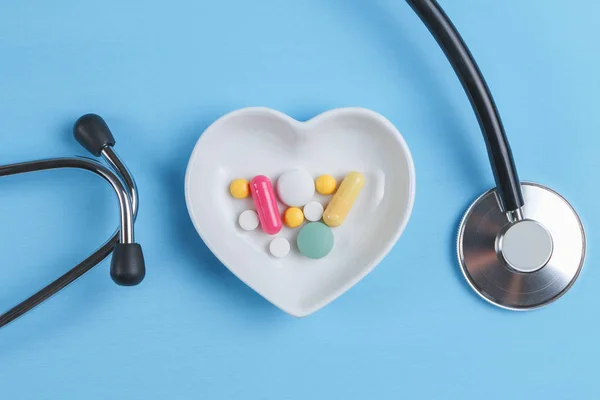 Steteskop ve çeşitli hap bir daire üzerinde kalp şeklinde bir