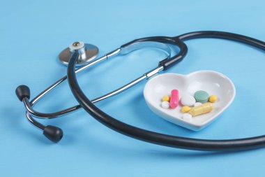 Steteskop ve çeşitli hap bir daire üzerinde kalp şeklinde bir