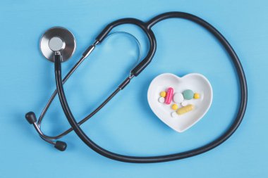Steteskop ve çeşitli hap bir daire üzerinde kalp şeklinde bir