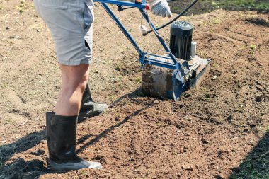 Bir adam bir elektrik Kültüvatör ile Bahçe toprağa pulluklar