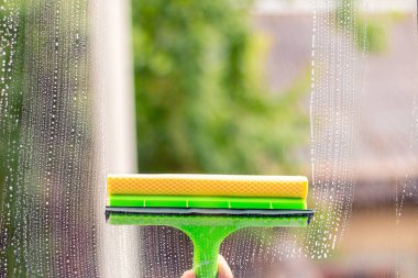 Window cleaner using a squeegee to wash a window clipart