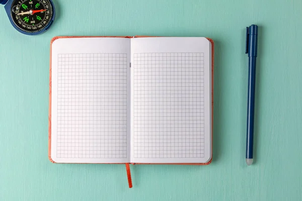 Cuaderno, bolígrafo y brújula sobre fondo verde — Foto de Stock