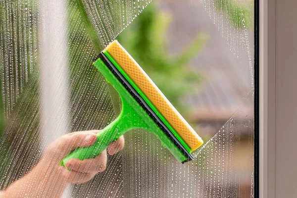 Window cleaner using a squeegee to wash a window