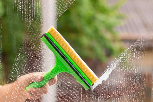 Pencereyi silmek için cam temizleyicisi kullanıyor.